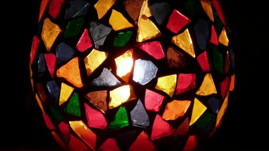 Buntes Windlicht aus Glas mit bunten Scherben, durch die das Licht einer Kerze scheint