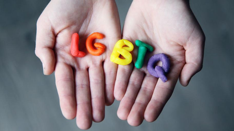 Auf einer Hand liegen die Buchstaben LGBTQ aus Knete geformt. 