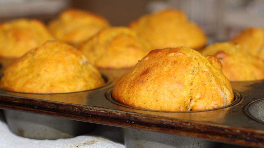 Orangene, gold-gelbe Muffins in einer Muffinform, hochgebacken