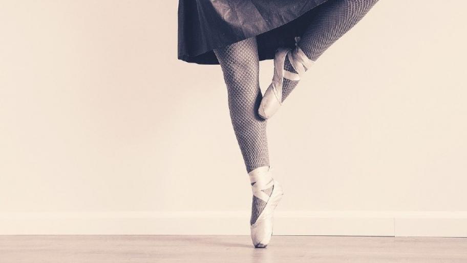 Eine Ballettpose: Ballettschuhe auf der Fußspitze mit angewinkeltem Bein 
