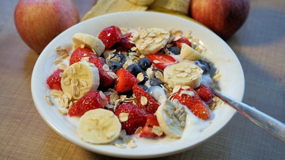 Foto von einer Schüssel mit Joghurt. Auf dem Joghurt sind Bananen, Himbeeren und Blaubeeren.
