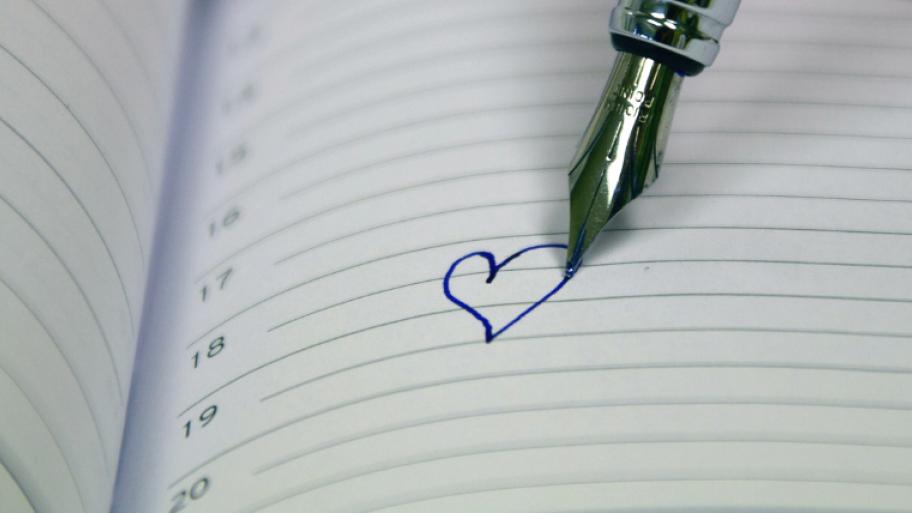 Ein Füller malt ein Herz in ein Tagebuch