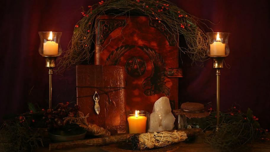Zu sehen ist eine Art Altar, dekoriert mit Kerzen und einem Zauberbuch. 