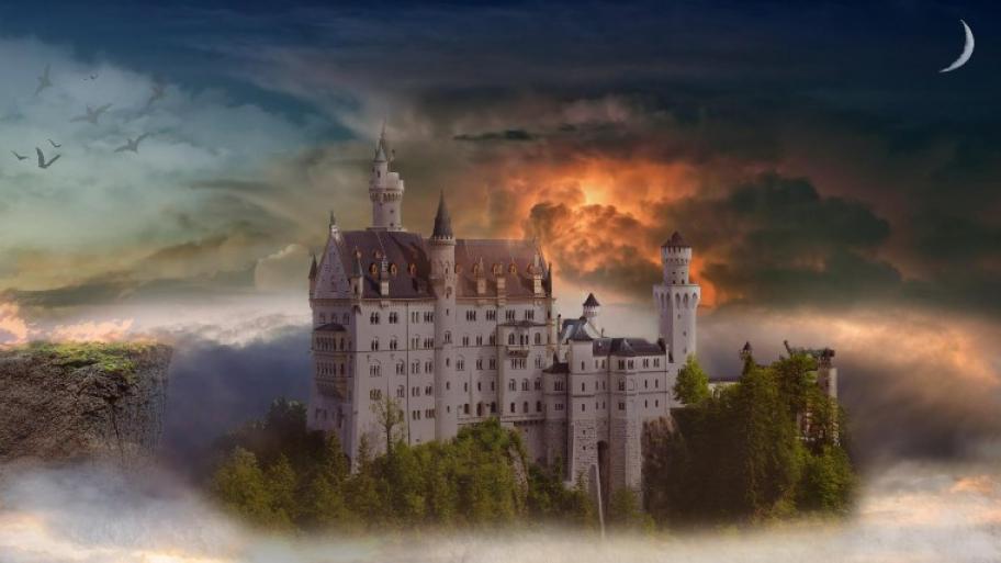 ein Schloss auf einem begrünten Schlosshügel umgeben von Wolkenbergen
