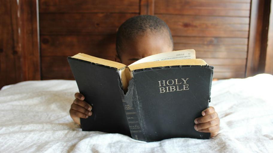 Ein Kind liest in der Bibel. 