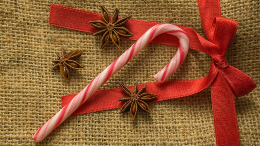 Weihnachtsdekoration; Zuckerstange, Schleife und Sternanis liegen auf Jutesack