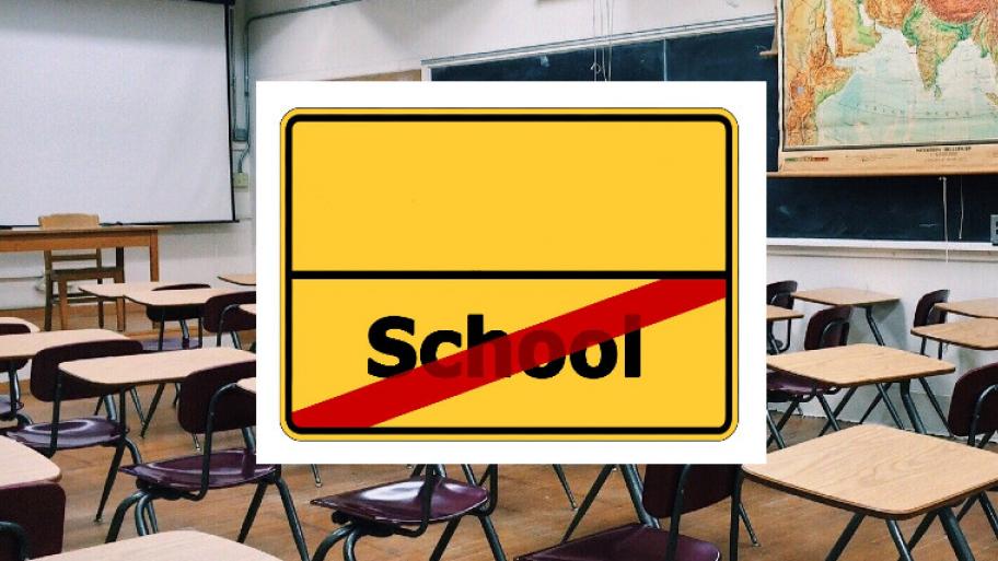 Ein leeres Klassenzimmer und ein Schild auf dem Schule durchgestrichen ist