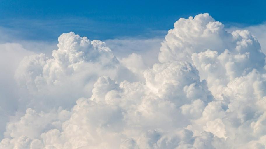weiße Schäfchenwolkenberge türmen sich auf, im Hintergrund strahlend blauer Himmel
