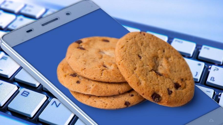 vier runde Kekse liegen aufeinandergestapelt auf einem Smartphone, darunter ist eine Tatstatur zu sehen