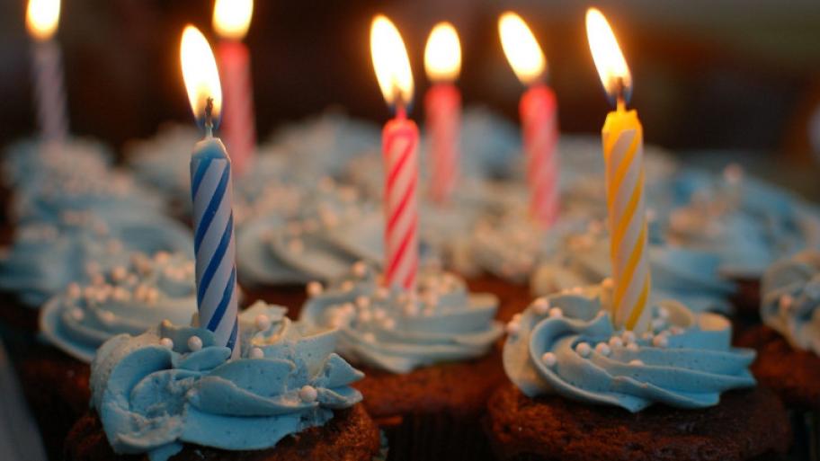 Cupcakes mit bunten brennenden Kerzen darauf