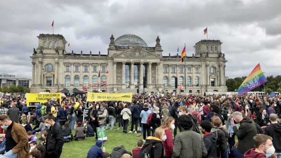 auf der Wiese vorm Reichstag viele Demonstrierende sitzend und stehend mit Transparenten und Plakaten