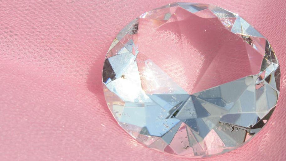 Ein großer Diamand liegt auf einem rosa Untergrund.