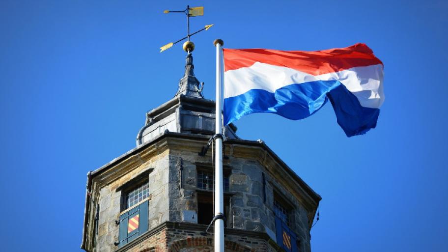niederländische Flagge vor blauem Himmel und Turm