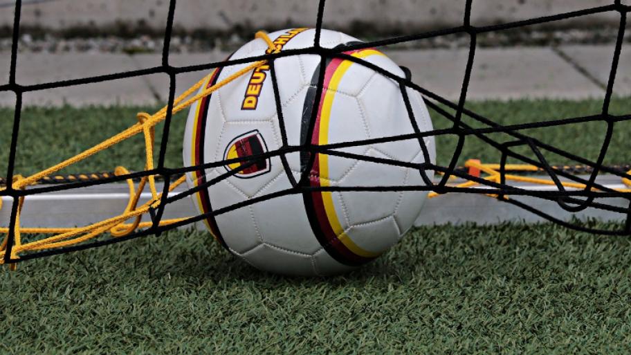 Ein Fußball im Tor mit schwarz-rot-gold-Farben