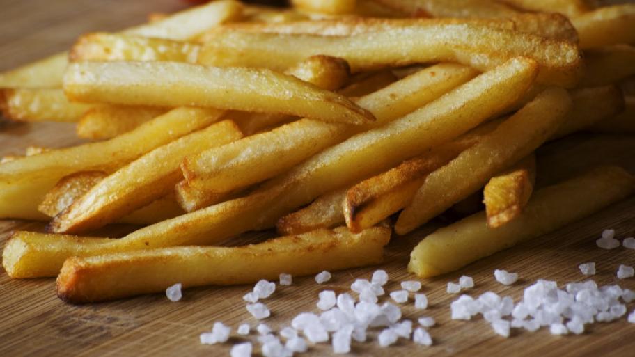 Pommes Frites auf Holzbrett, vorne grobes Salz