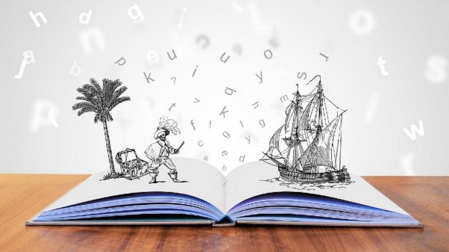 Ein offenes, weißes Buch auf einem Holztisch. Daraus kommen Buchstaben, die in der Luft wirbeln.