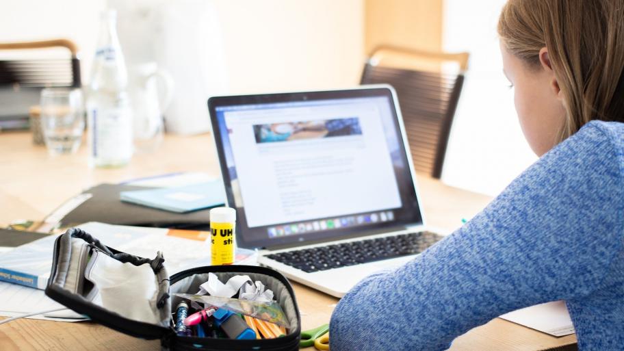 Ein Mädchen sitzt gegenüber von einem Laptop an einem Schreibtisch