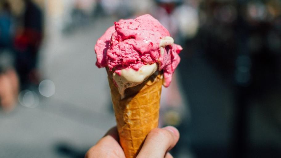 Ein Foto von einem Menschen, der eine Eiswaffel mit zwei Kugeln in der Hand hält.