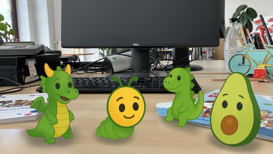 Auf einem Schreibtisch stehen nebeneinandern gezeichnete Emojis. Ein Drache, eine Raupe, ein Dino und eine Avocado.