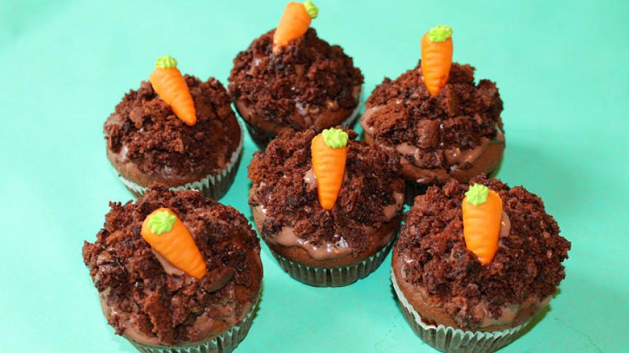 auf türkisem Untergrund stehen 6 Schokomuffins, jeder dekoriert mit einer orangenen Marzipan-Möhre