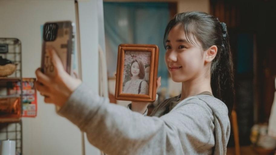 ein Mädchen macht ein selfi, in der Hand ein Foto von ihrer Mutter