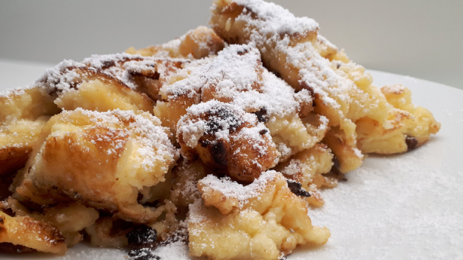 auf einem weißen Teller angerichtet ein Berg Kaiserschmarrn, mit Puderzucker bestäubt
