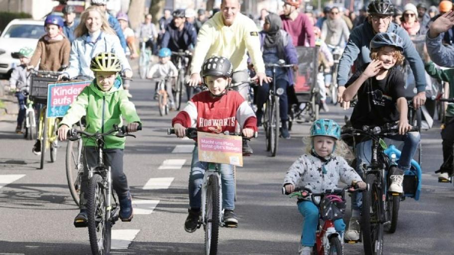 Kidical Mass Fahrraddemonstration: auf einer Straße fahren viele Kinder und Erwachsene auf Fahrrädern
