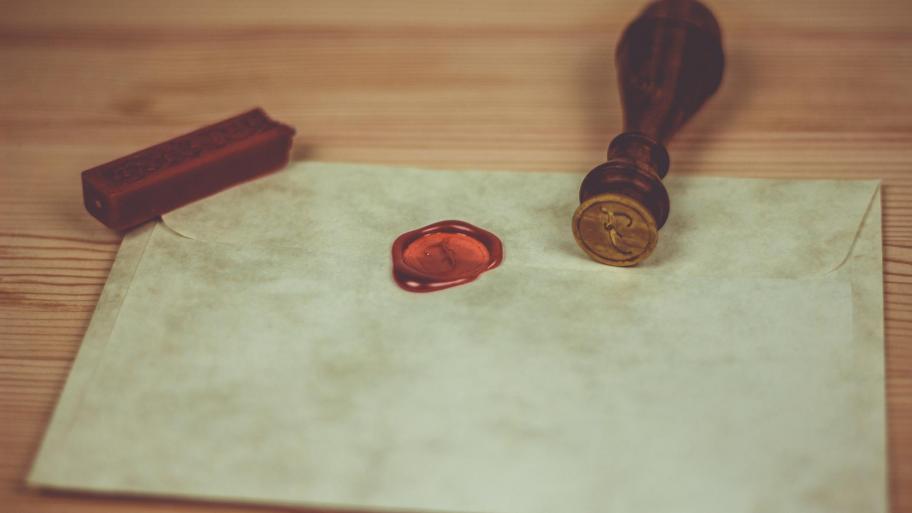 heller Brief mit einem roten Siegel darauf, der auf einem Holztisch liegt