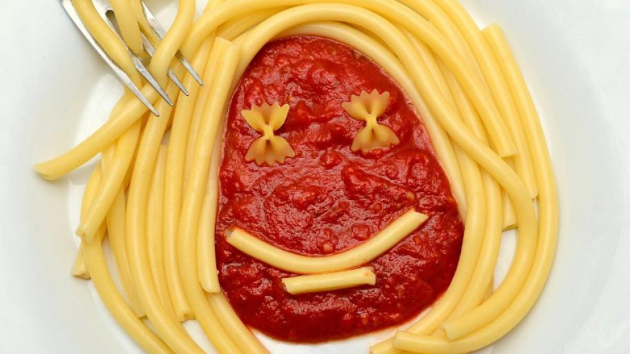 Nudeln mit Tomatensoße; es wurde ein Gesicht gelegt, wobei die Nudeln die Augen, der Mund und die Haare sind und die Tomatensoße das Gesicht