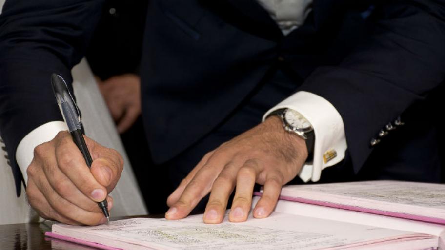 Ein Mann im Anzug unterschreibt einen Vertrag. 
