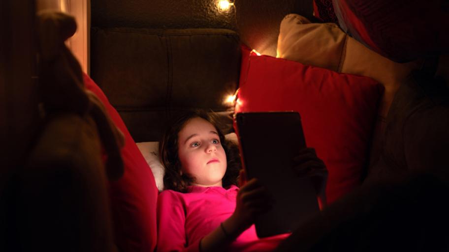 Ein Mädchen schaut im Dunkeln auf ihr Tablet