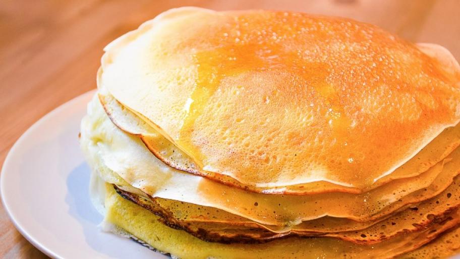 ein Stapel frisch gebackener Pfannkuchen liegt auf einem weißen Teller