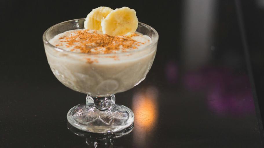 Bananeneis im Kelch mit Zimt bestreut und zwei Bananenscheiben, die an der Seite stecken
