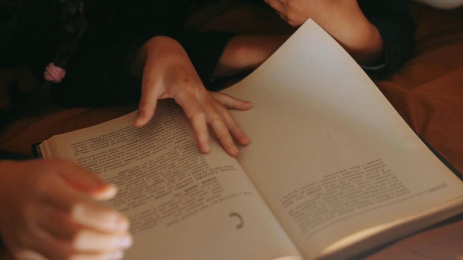 Aufgeklapptes Buch von oben, Kinderhände halten Buchseiten auf
