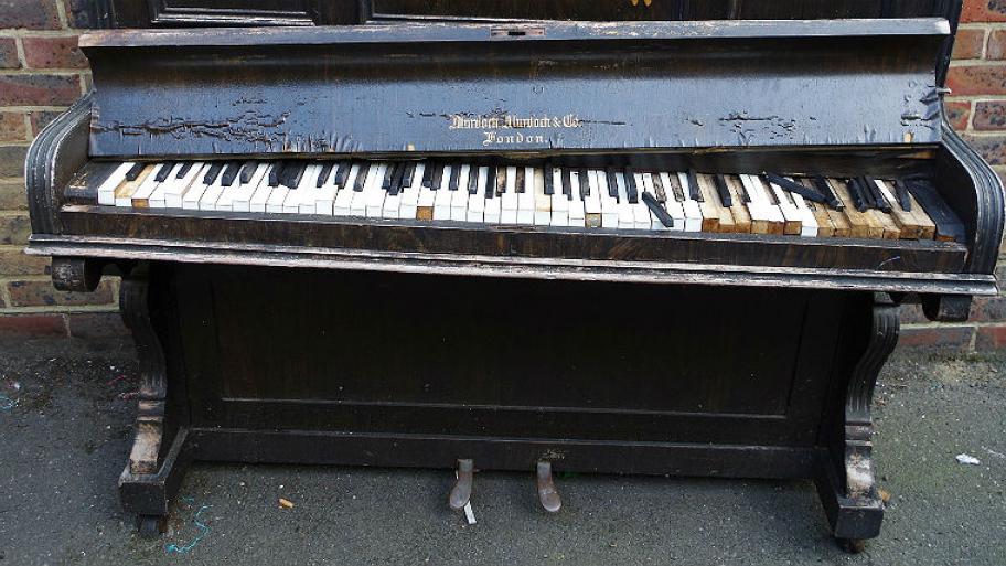 Ein kaputtes Klavier steht in einer Straße.