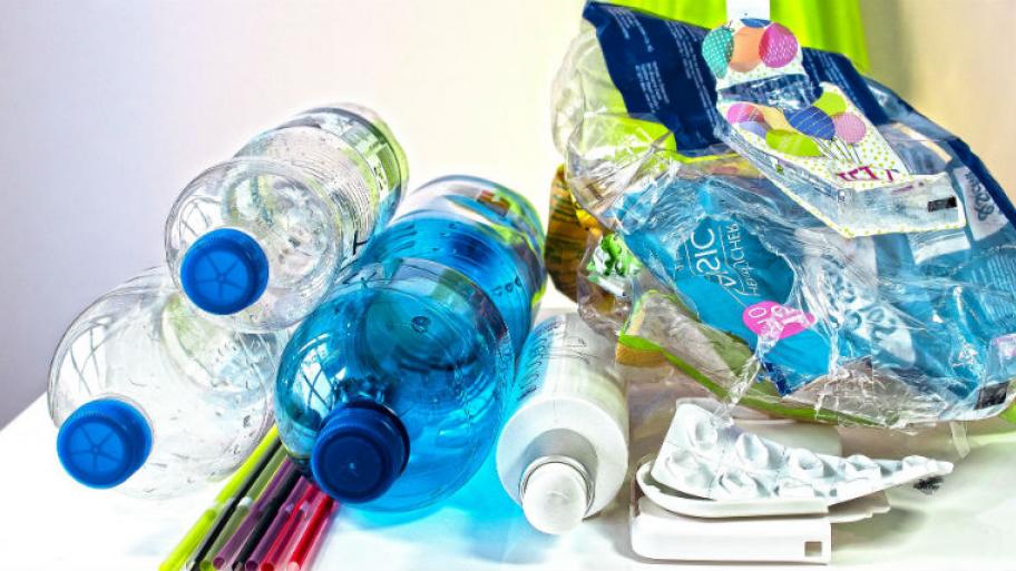 Plastikflaschen, Strohhalme und Verpackungen liegen auf einem Tisch.