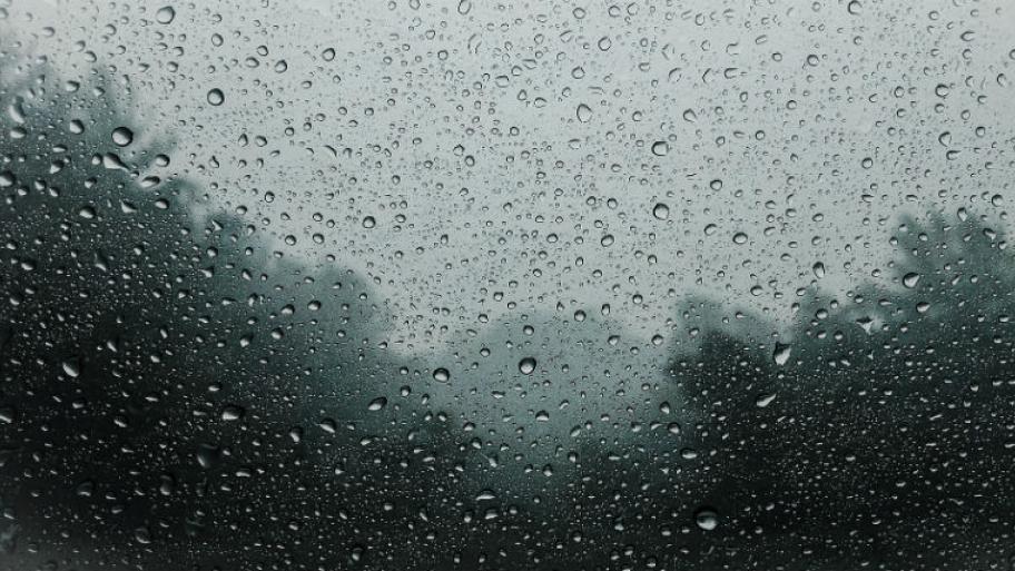 Regentropfen an einem Fenster. Alles sieht grau aus. 