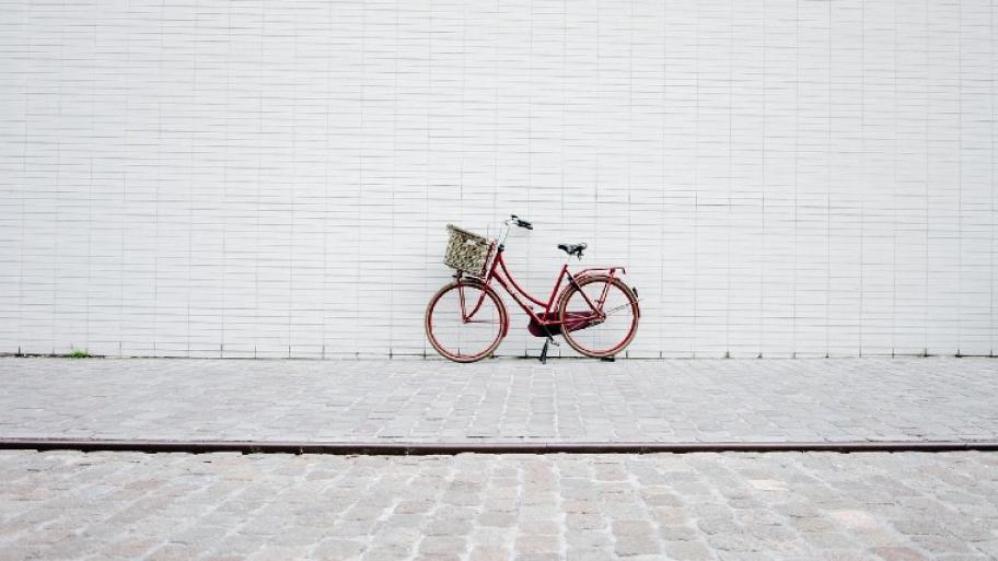 Ein rotes Fahrrad steht vor einer weißen Wand.