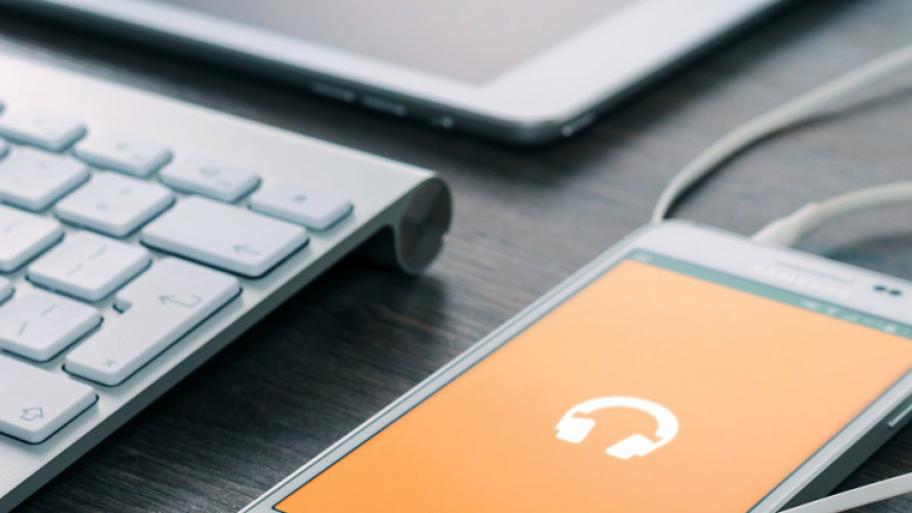 Handy Hintergrund orange mit Piktogramm Kopfhörer, weiße Tastatur und Tablet