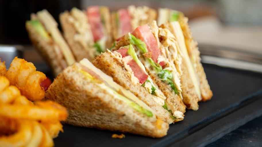 Einige dreickig geschnittene Toastscheiben. Sie sind verschieden belegt, zum Beispiel mit Salat, Tomate und Käse.