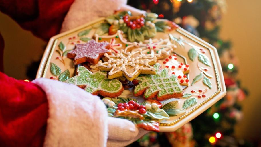 Keksteller mit Ausstechplätzchen, bunt verziert; Person im Weihnachtsmann-Kostüm hält den Keksteller