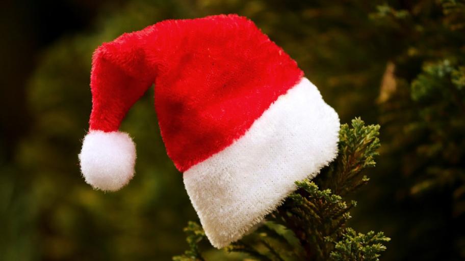 Weihnachtsmannmütze ist über Tannenzwei gestülpt 