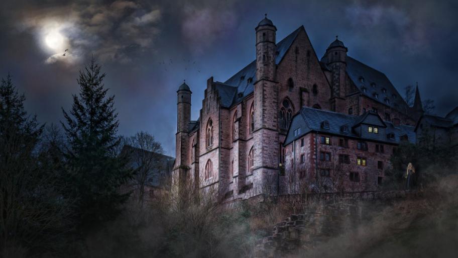 Altes Schloss aus Backstein wird nachts vom Vollmond angeleuchtet