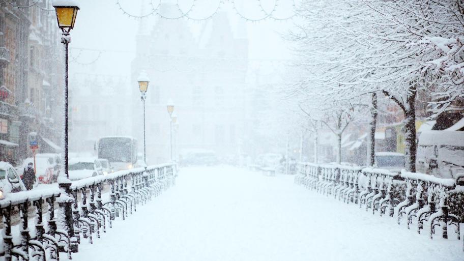Eine schneebedeckte Straße mit Laternen und Autos. 