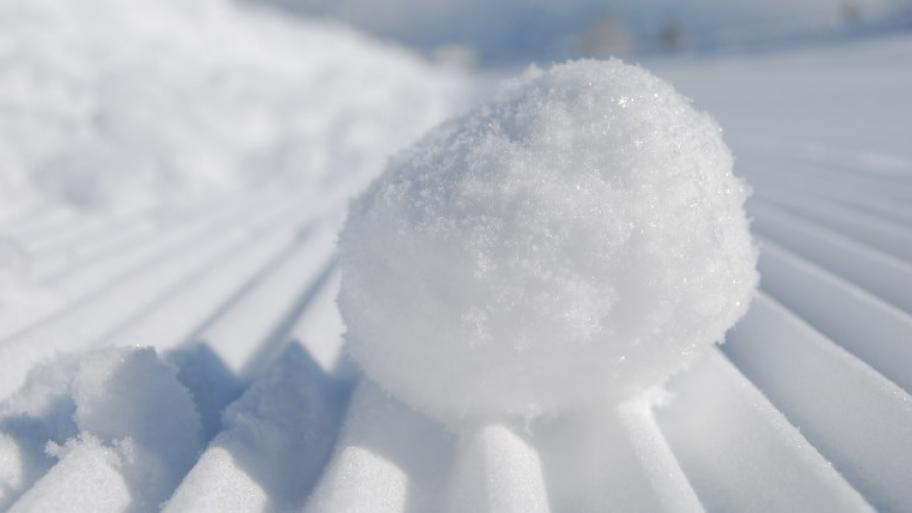 ein weißer, runder Schneeball liegt mittig im Bild auf einer weißen Unterlage