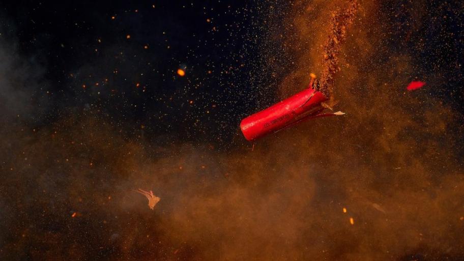 ein roter Böller explodiert in der Luft, dunkler Hintergrund