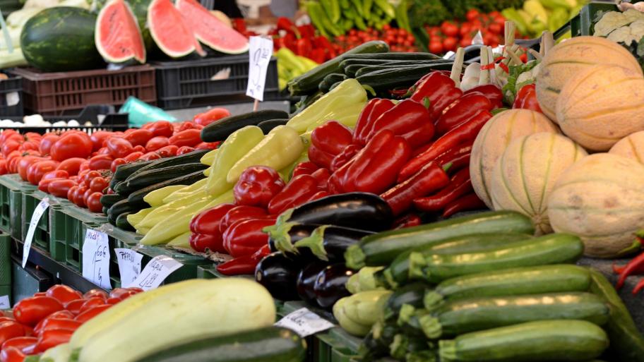 Zu sehen sind ein paar Gemüsestände auf einem Marktplatz. 