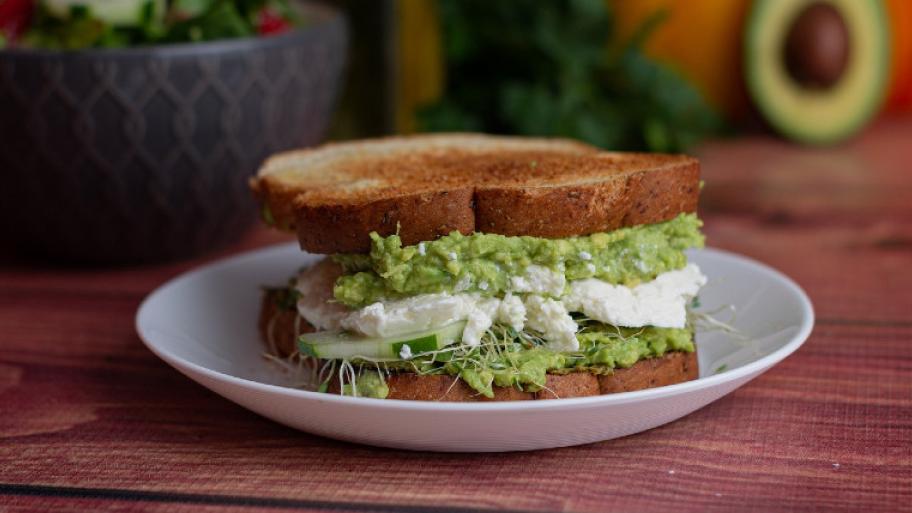 Ein belegtes Sandwich mit Avocado und Frischkäse.