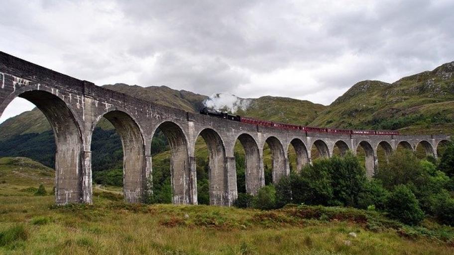 Roter Zug fährt über Brücke in Schottland