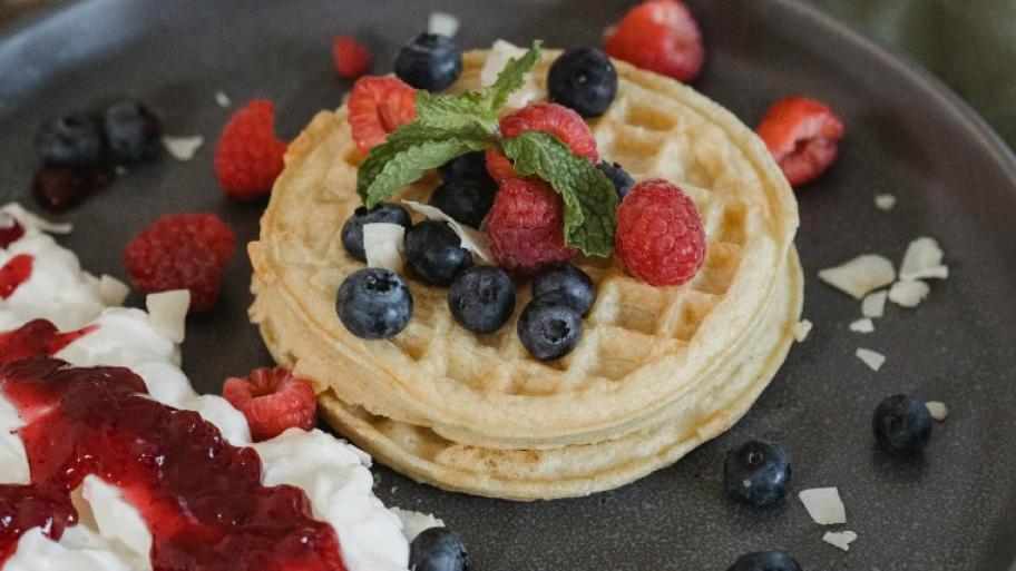 Ein Teller mit Waffeln und bunten Beeren.